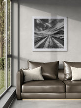 Load image into Gallery viewer, Framed Long Straight black and white fine art print displayed in a contemporary interior beside a window.