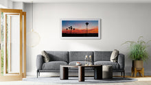 Load image into Gallery viewer, Framed West Coast sunset landscape photograph with nikau palms displayed in a contemporary living room with a white frame
