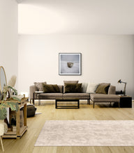 Load image into Gallery viewer, Lone Rock surrounded by moving water at Okarito framed in a modern living area with a low grey brown couch