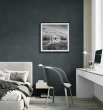 Load image into Gallery viewer, Framed Old Tin Hut black and white landscape print displayed in a dark contemporary bedroom.