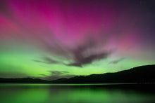 Load image into Gallery viewer, Pink and green Aurora Australis reflected over the water at Stewart Island, New Zealand