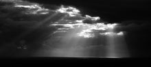 Load image into Gallery viewer, Black and white photograph of sun rays breaking through dark clouds over the Tasman Sea at North Beach, West Coast New Zealand